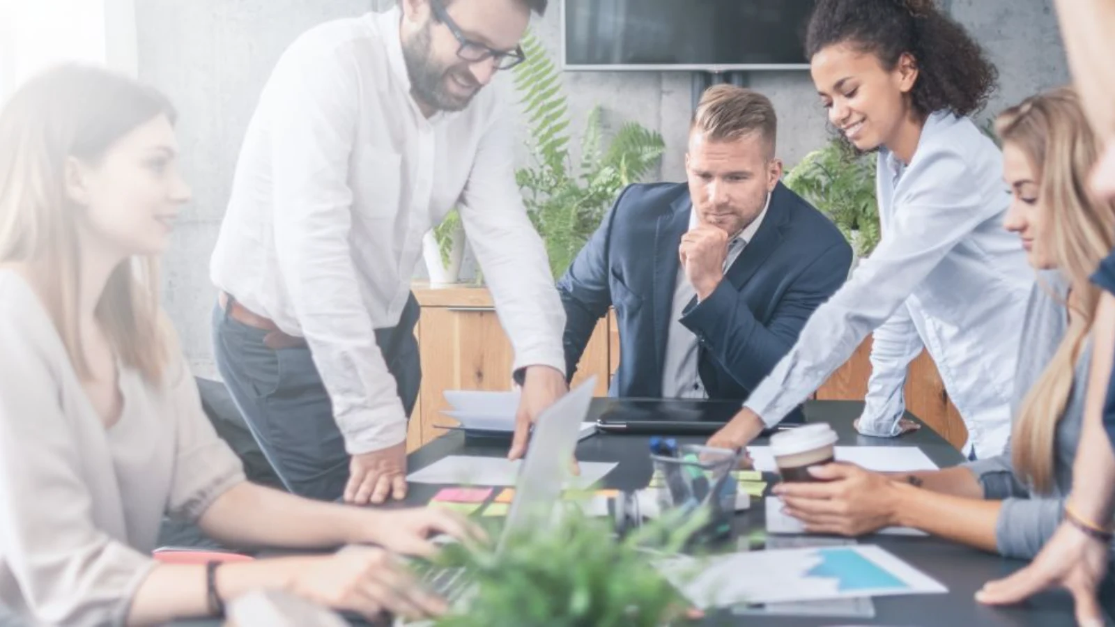 Diverse corporate team and financial analysts collaborating around a conference table reviewing Power BI budget reports, forecasts, and business metrics